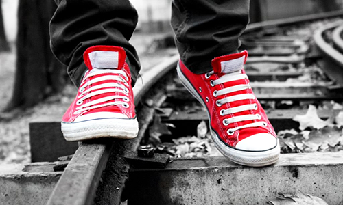 red and white shoes walking a black and white train track